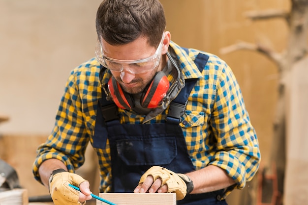 Free Photo close-up of a male carpenter wearing safety glasses working in the workshop