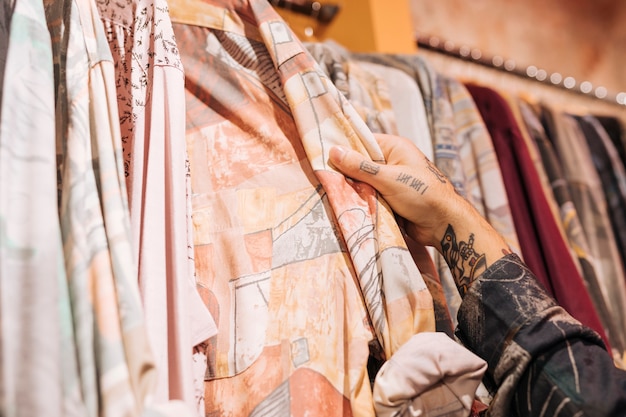 Free photo close-up of male customer's hand choosing the shirt hanging on the rail in the shop