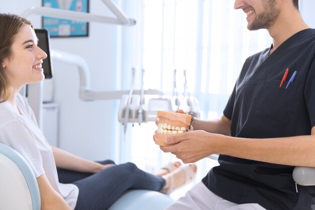 Close-up of a male dentist showing teeth model to patient