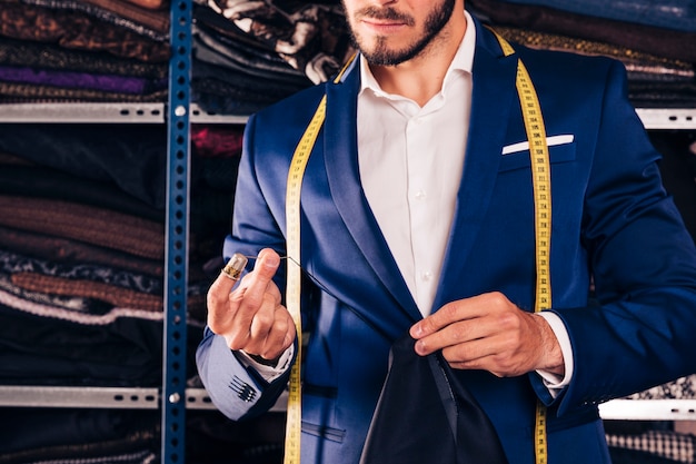 Close-up of a male fashion designer sewing fabric with needle in his workshop