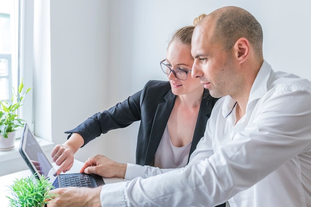 Free photo close-up of male and female businesspeople working on laptop at workplace