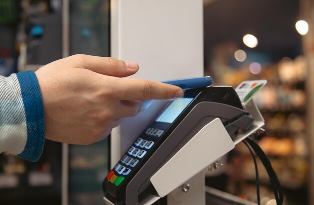 Close up of male hand holding smartphone in payment terminal