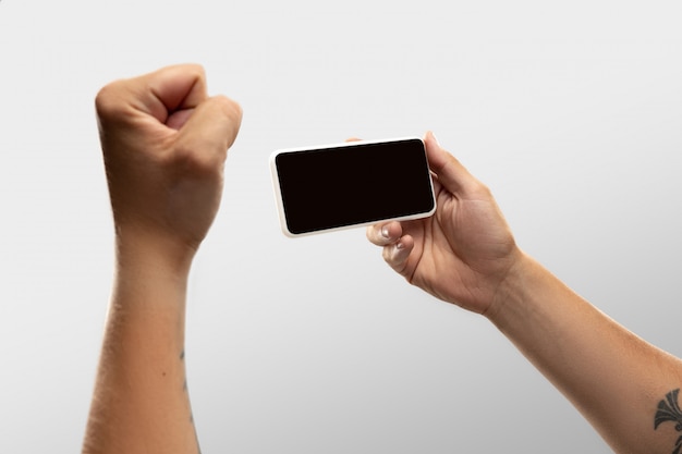 Close up male hands holding phone with blank screen during online watching of popular sport matches and championships all around world.