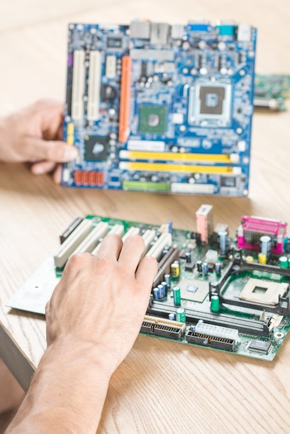 Free Photo close-up of male hands practicing to repair motherboard on wooden table