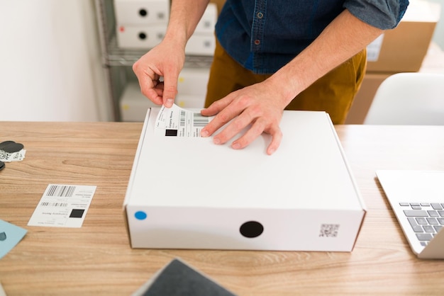 Close up of male hands putting a shipping label on a package and arranging online customers' orders