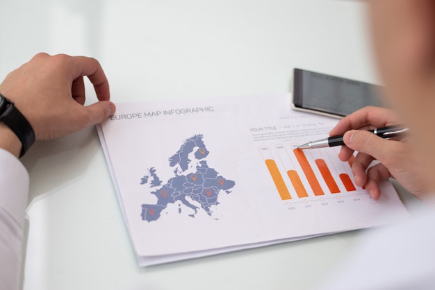 Close-up of male hands working with Europe sale statistic report