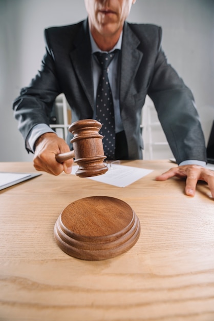 Free photo close-up of male judge giving verdict by hitting gavel at desk