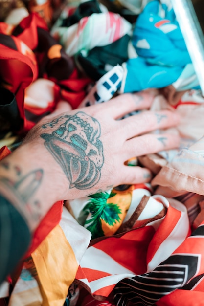 Free photo close-up of male's hand with tattoo touching scarf in shop