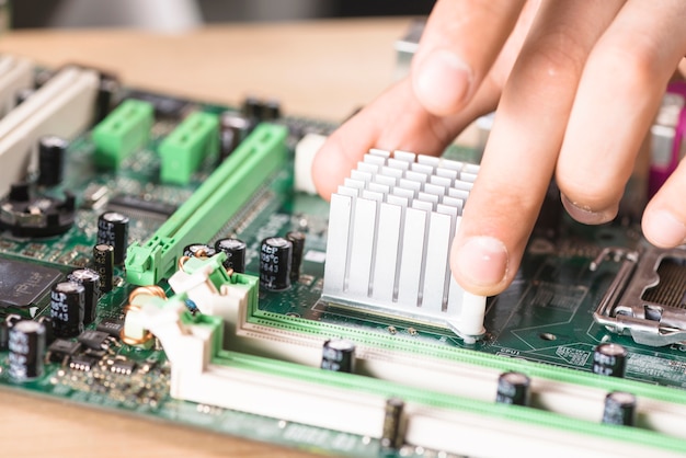 Free photo close-up of male technician hand's installing heatsink on computer main-board