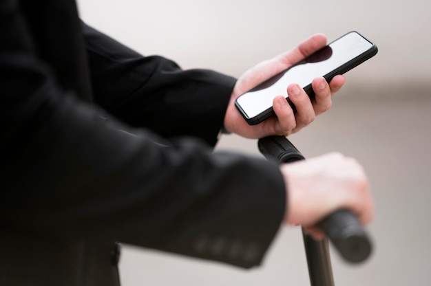 Close-up male using scooter with mobile phone