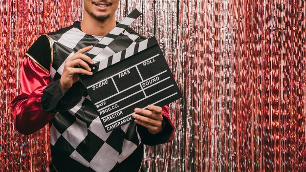 Free photo close-up male with film slate at carnival party