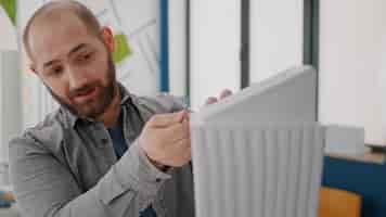 Free photo close up of man analyzing building model with woman using blueprints plan on table. colleagues working together to design construction structure and layout for urban development.