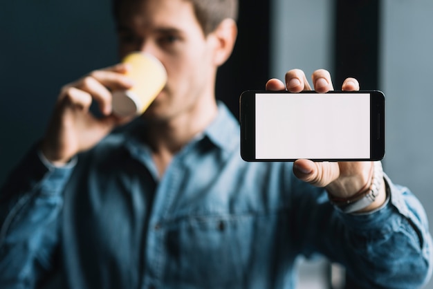 Free photo close-up of a man drinking coffee showing mobilephone