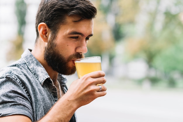 Close-up of man drinking glass of beer at outdoors