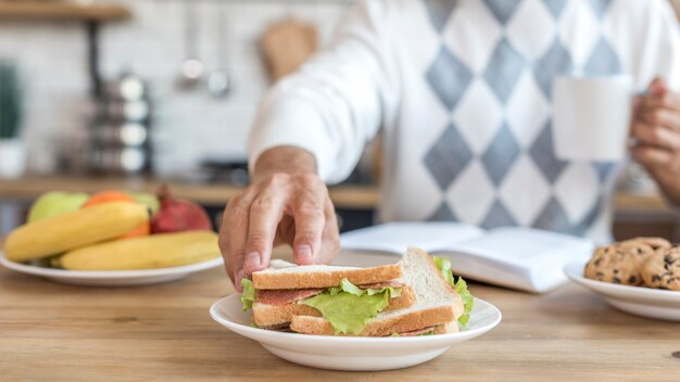 Close-up man eating healthy sandwiches in the kitchen