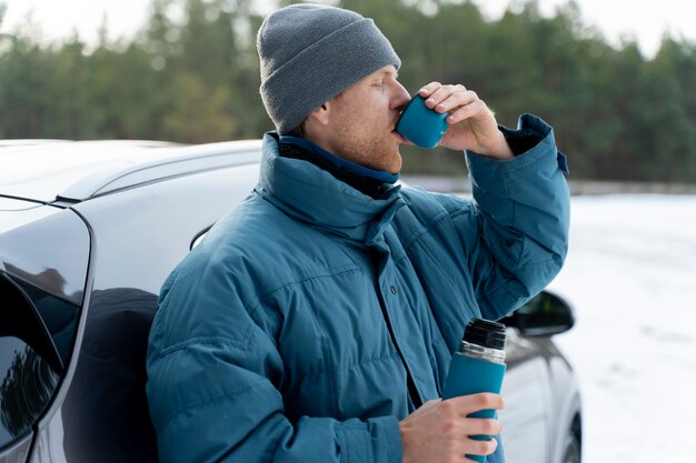 Close up on man enjoying hot drink while on winter trip