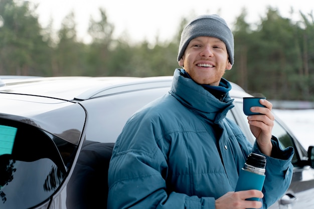 Close up on man enjoying hot drink while on winter trip