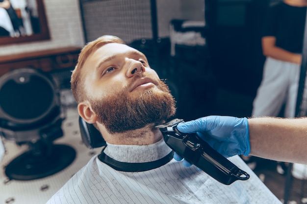 Close up man getting hair cut at the barbershop wearing mask during coronavirus pandemic.