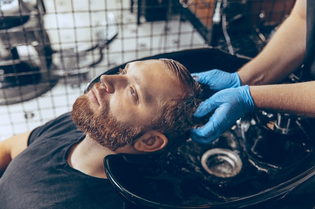 Free photo close up man getting hair cut at the barbershop wearing mask during coronavirus pandemic.