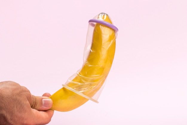 Free photo close-up man holding a banana with condom