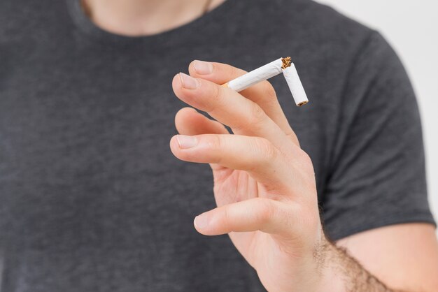 Close-up of man holding the broken cigarette in his two finger