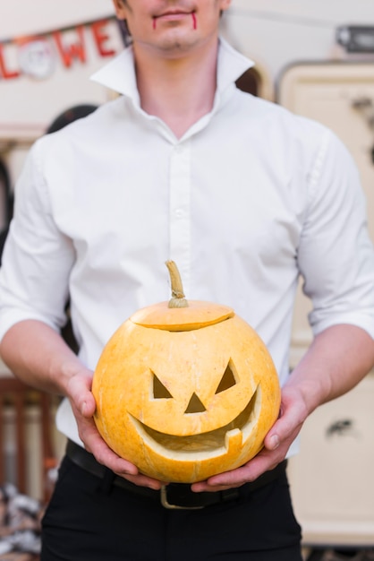 Close-up man holding carved pumpkin