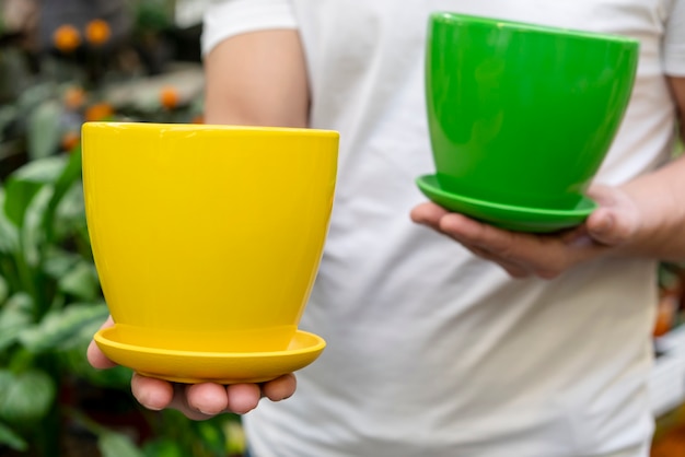 Close-up man holding colorful flowerpots