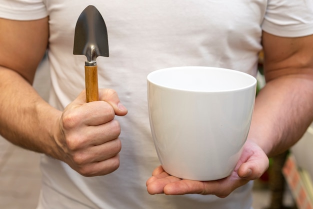 Close-up man holding flower pot and gardening tools