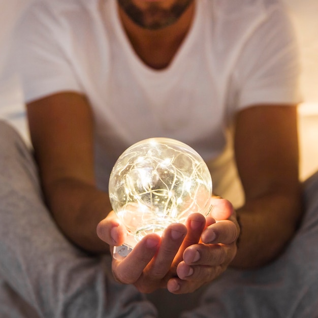 Close-up of man holding glowing transparent sphere