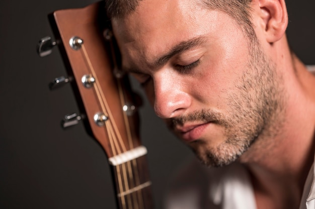 Close-up man holding his head on guitar headstock