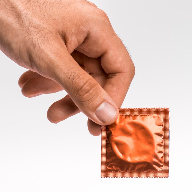 Close-up man holding an orange condom