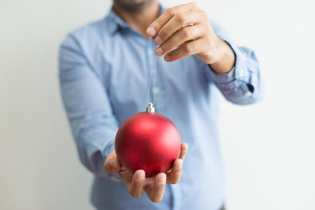 Close-up of man holding red bauble on string