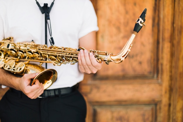 Free Photo close up of man holding tightly sax