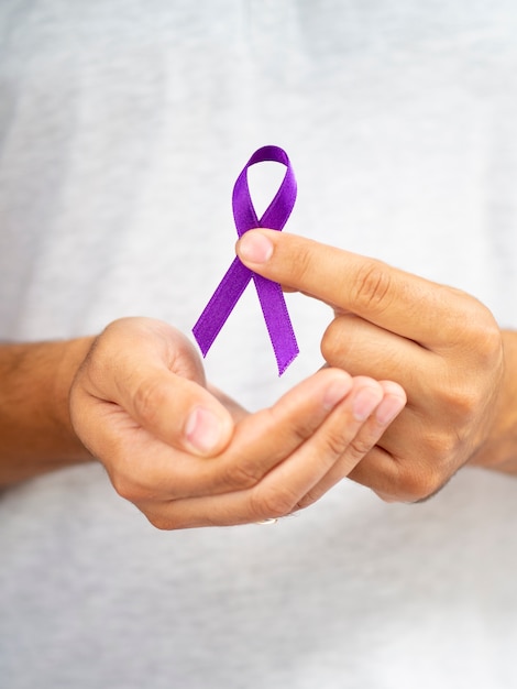 Free photo close-up man holding up purple ribbon