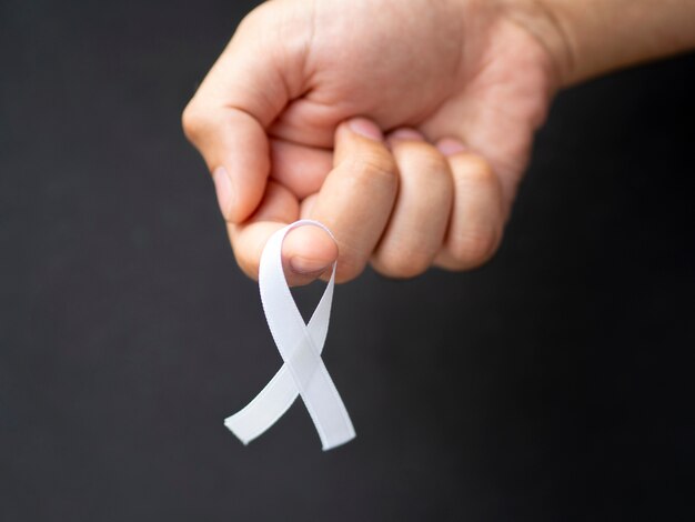 Close-up man holding up white ribbon