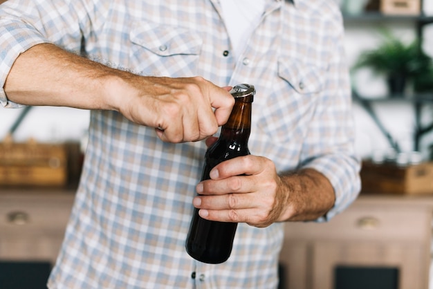 Free Photo close-up of a man opening the beer bottle with opener