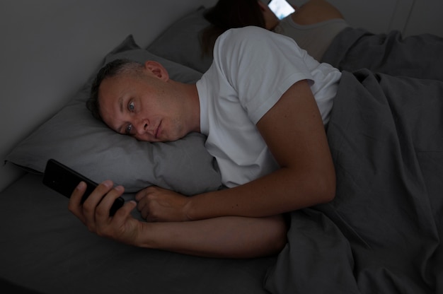 Free Photo close up on man on phone in bedroom