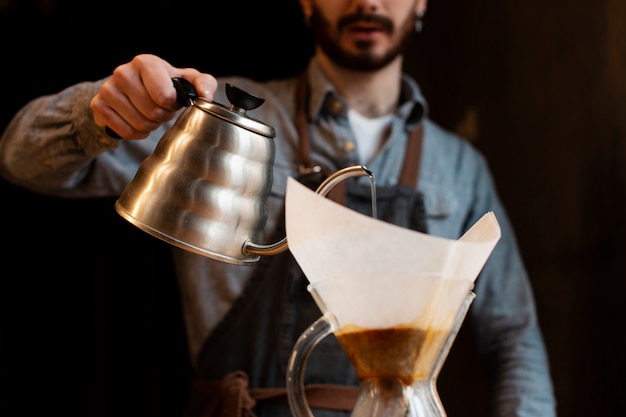 Free photo close-up of man pouring coffee from pot in filter