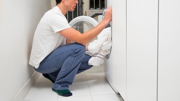 Free photo close-up of a man putting clothes in the washing machine