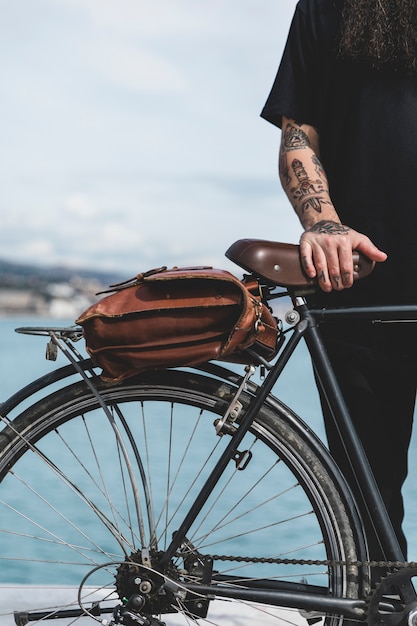 Free photo close-up of man's hand on bicycle with brown bag