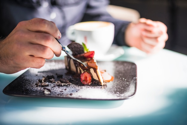 Free Photo close-up of man's hand eating cake with fork