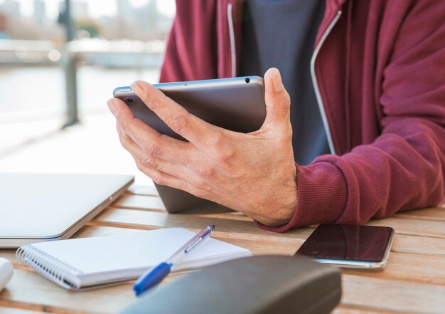 Close-up of man's hand holding digital tablet in hand at outdoors caf�