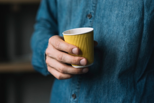 Free photo close-up of a man's hand holding disposable coffee cup