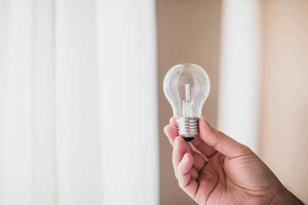 Close-up of man's hand holding transparent light bulb