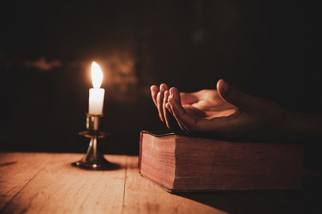 Free Photo close up man's hand is praying in the church with lit candle