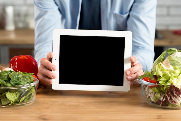 Close-up of man's hand showing digital tablet with blank screen in kitchen