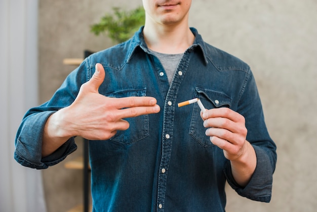 Close-up of man's hand showing gun gesture near the broken cigarette