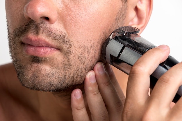 Close-up of man shaving with black trimmer