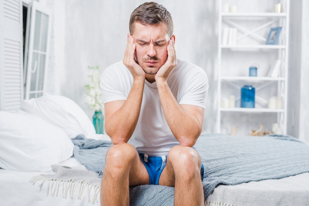 Free photo close-up of a man sitting on bed having headache