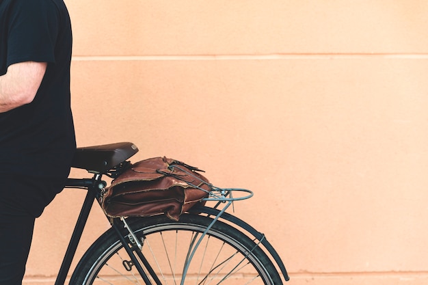 Free Photo close-up of a man sitting on bicycle against beige wall